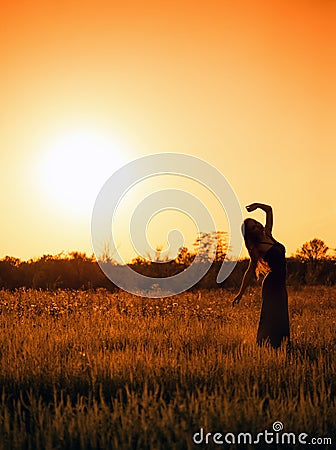 Silhouette of dancing young girl in dress against the sunset sky