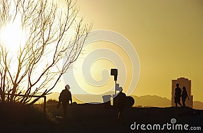 Silhouette of different people walking beach track