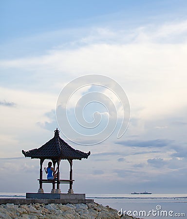 Silhouette of the girl sitting in a yoga posture on the pier