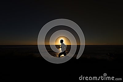 Silhouette of jogger along ocean horizon at sunset