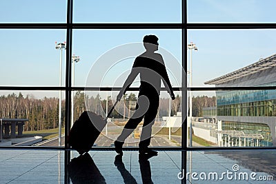 Silhouette of man with luggage near window