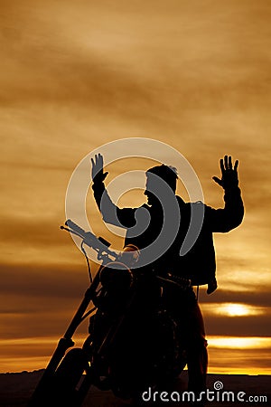 Silhouette of a man on a motorcycle hands up