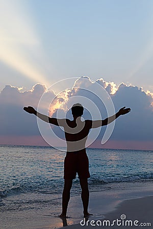 Silhouette Of Man With Outstretched Arms On Beach