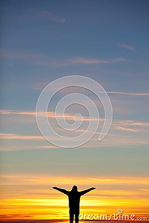 Silhouette of man spreading arms at sunset