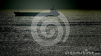 Silhouette of a merchant ship in a twilight sea