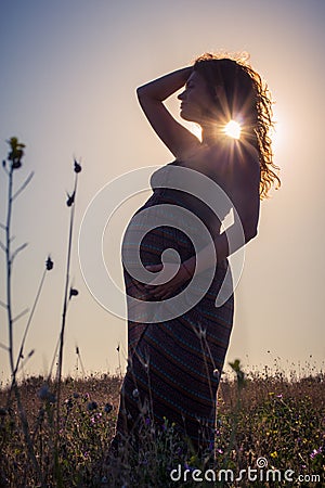 Silhouette of a pregnant woman at sunset