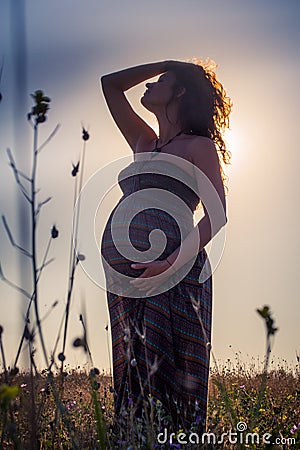 Silhouette of a pregnant woman at sunset