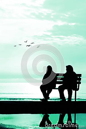 Silhouette of two friends sitting on wood bench near beach