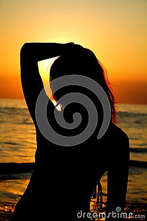 Silhouette of a woman against the ocean at sunset.
