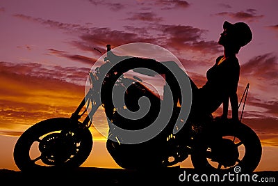 Silhouette of woman sit back on motorcycle hat on