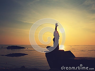 Silhouette yoga girl by the beach at sunrise doing meditation