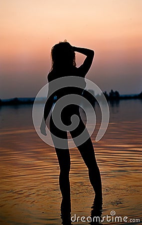 Silhouette of a young sensual woman in a river water