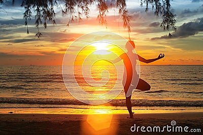 Silhouette young woman practicing yoga on the beach at sunset. Nature.