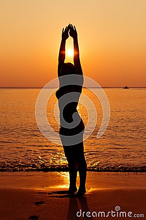 Silhouette of young woman in sea on sunset