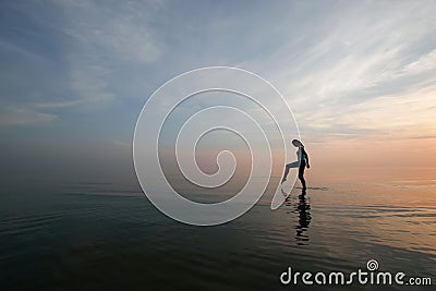 Silhouette of young woman wading in sea