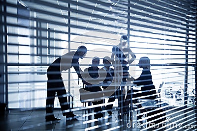 Silhouettes of business people through the blinds