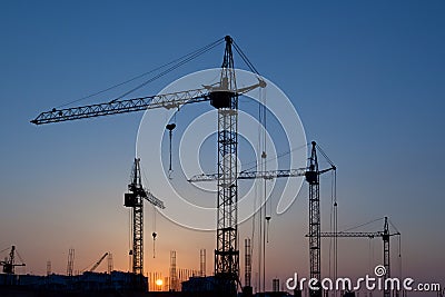 Silhouettes of construction cranes