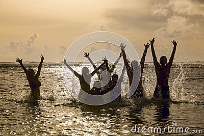 Silhouettes of people jumping in ocean