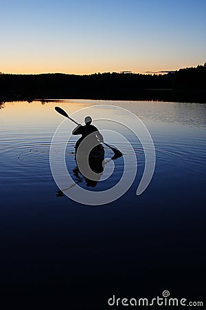 Sillouette of man kayaking on lake