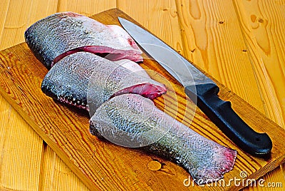 Silver carp steak and knife on wooden board