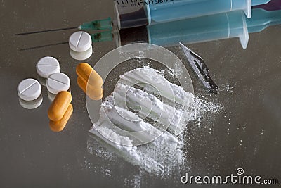 Single syringe, pills, blade and depiction of cocaine on mirror with wooden human figure