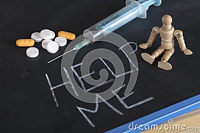 Single syringe, pills and wooden human figure on chalkboard with help me