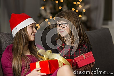 Sisters with Christmas presents looking at each other on sofa