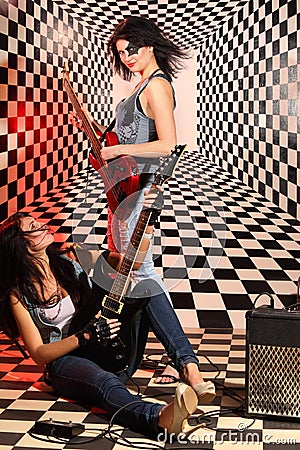 Sitting and standing women play electric guitar in studio