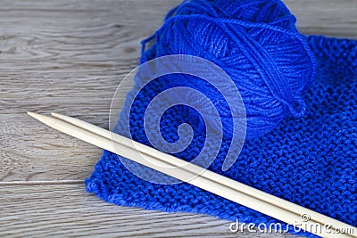 Skein of Blue yarn with completed knitting and bamboo needles
