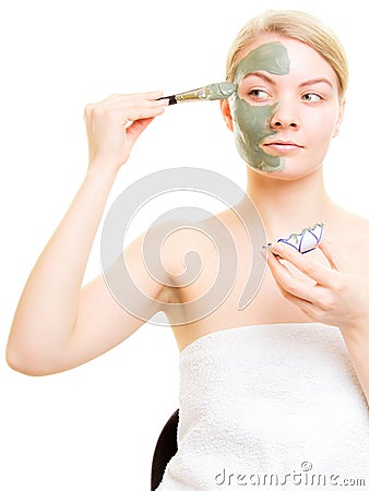 Skin care. Woman applying clay mud mask on face.