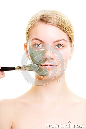 Skin care. Woman applying clay mud mask on face.