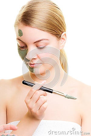 Skin care. Woman applying clay mud mask on face.