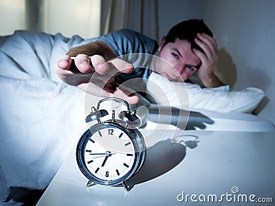 Sleeping man disturbed by alarm clock early mornin