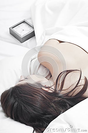 Sleeping woman in white sheets with a clock