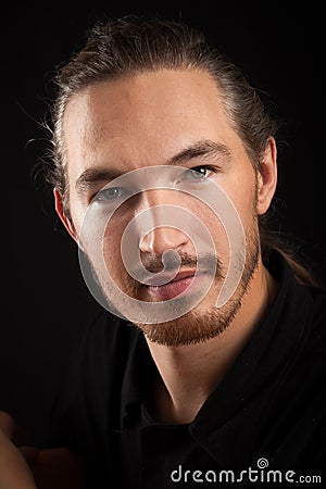 Slightly smiling young smart Oriental man portrait on black back