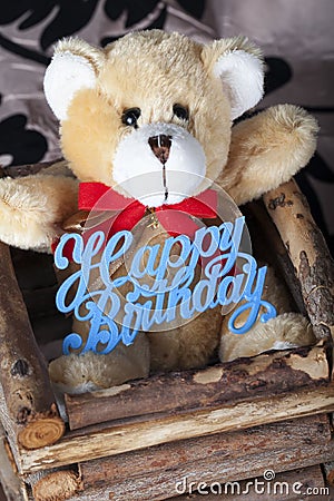 Small brown teddy bear with happy birthday sign