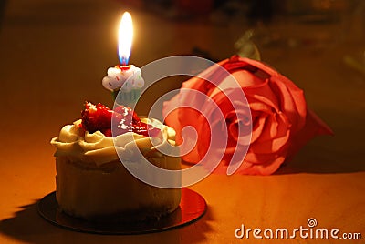 Small cake with a single candle and rose