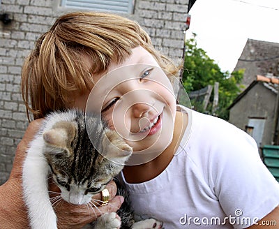 A small child hugging a kitten