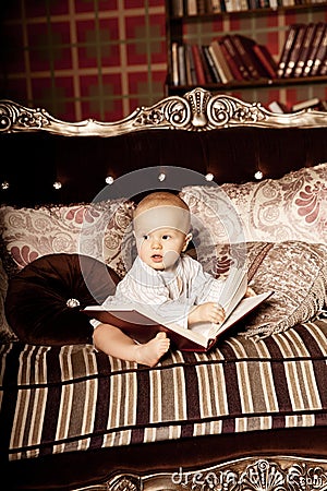 Small child in the interior reading a book. Smiling baby in the