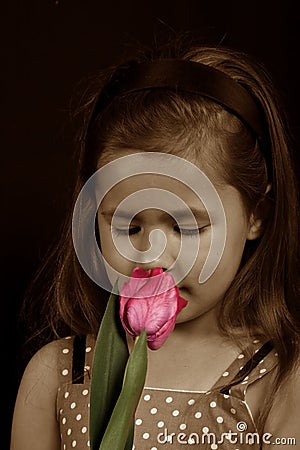 A small girl smelling a flower