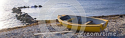 Small row boat laying on a pebble beach