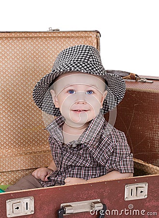 Small smiling boy sits in an open road suitcase.