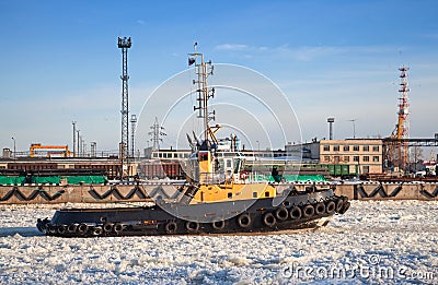 Small tug boat goes through icy channel in harbor of St.Petersburg 