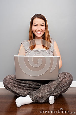 Smiley woman with laptop sitting on floor