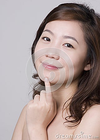 Smiling Asian girl with a finger touching her chin