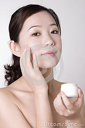 Smiling Asian girl with a lotion on her hand