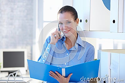 Smiling assistant on phone call holding folder
