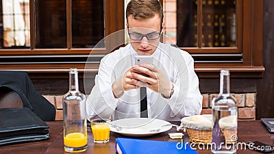 Smiling attractive Businessman sitting with smartphone in restaurant.