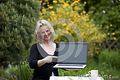 Smiling beautiful blond woman pointing at laptop