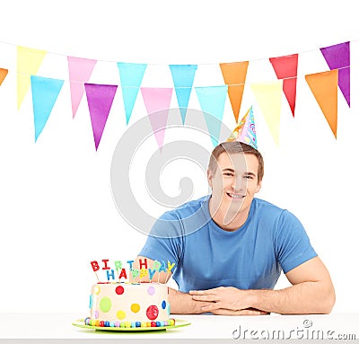 Smiling birthday guy with a party hat and a cake